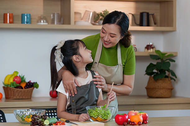istock Cooking Together. Parent and child sharing a smile while preparing salad in a cozy kitchen. 2234423316