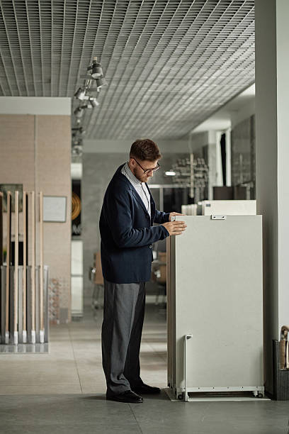istock Caucasian Man Examining Display Stand in Modern Showroom 2234427042