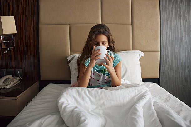 istock Adorable little girl drinking tea in bed 2234431135