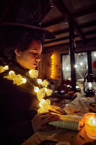 istock Black woman dressed as a witch reading a book on Halloween. 2234431881