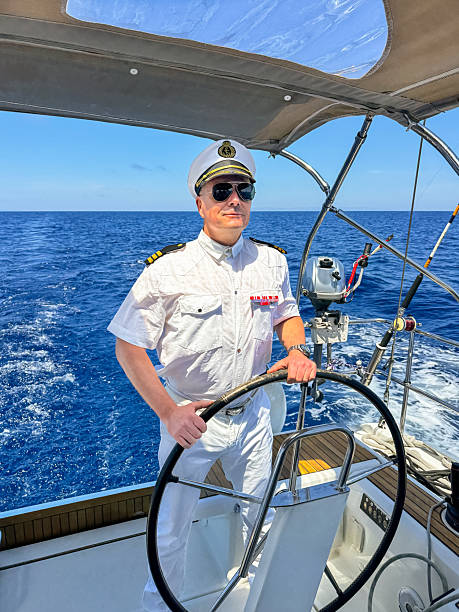 Skipper dressed like an admiral sailing holding steering wheel.