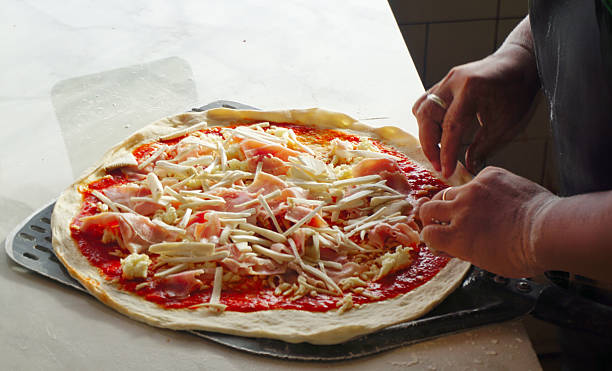 istock Chef placing cheese on pizza with hand, Close up shot 2234437410