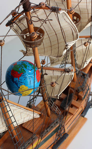 istock Globe model on the rigging ropes of an old sailing ship on white background 2234439123