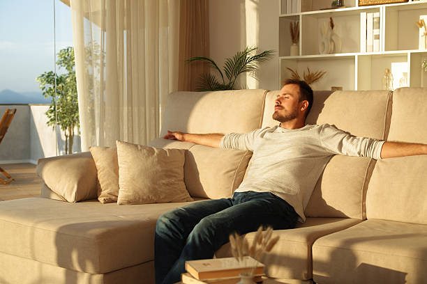 istock Man relaxing at sunset at home sitting on a couch 2234441136