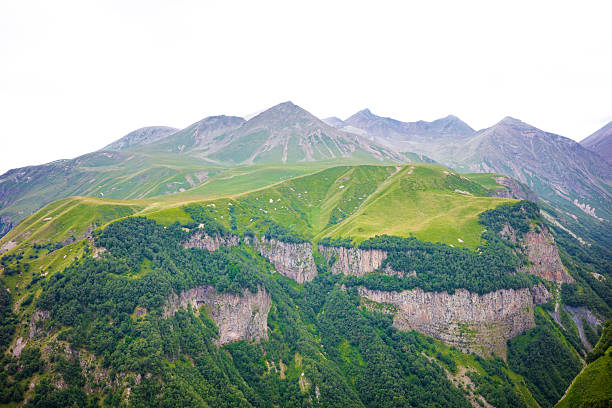A stunning landscape of towering green ridges, dramatic rocky cliffs, and distant mountain peaks. A breathtaking view of untouched wilderness, perfect for hiking, travel inspiration, and outdoor adventure themes