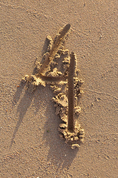 Number four written on a sandy beach. Handwritten characters collection.