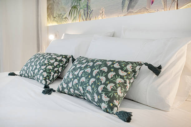 istock Neatly made matrimonial double bed with crisp white linens and accented green decorative cushions 2234450430
