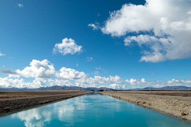 Clouds reflect off the turquoise water of Pukaki Canal in the southern alps of the South Island. The canal takes water from glacial lakes for hydro power and urban water supplies. This image was taken on a cold and sunny morning on 6 September 2025.