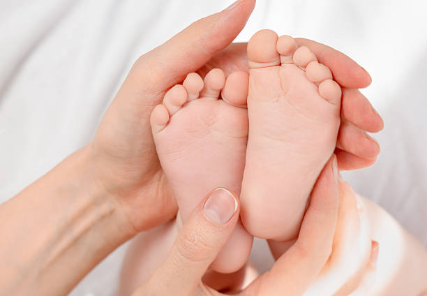 istock baby's feet in female hands 2234452063