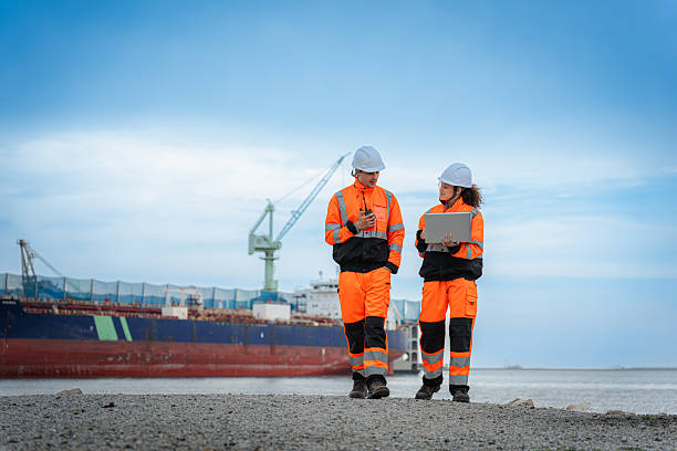 istock Team of Maritime Engineers Overseeing Work at Shipyard Construction Site, Dock Workers in Safety Uniforms Coordinating Operations and Planning and Managing Tasks with Technology 2234452157
