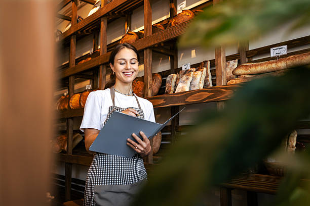 istock Smiling bakery owner writing checklist in her shop 2234453392