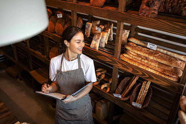istock Female entrepreneur managing bakery operations with clipboard 2234453400