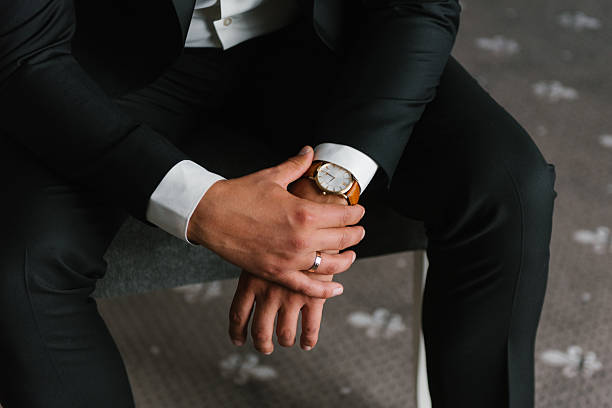 Groom Sitting In Black Suit With Watch