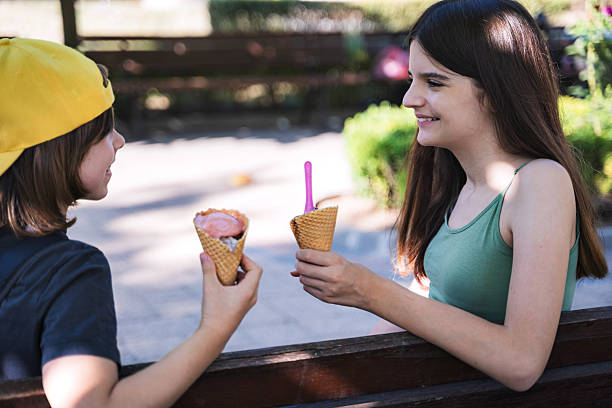 istock Kids enjoying ice cream while sitting on a park bench 2234455969