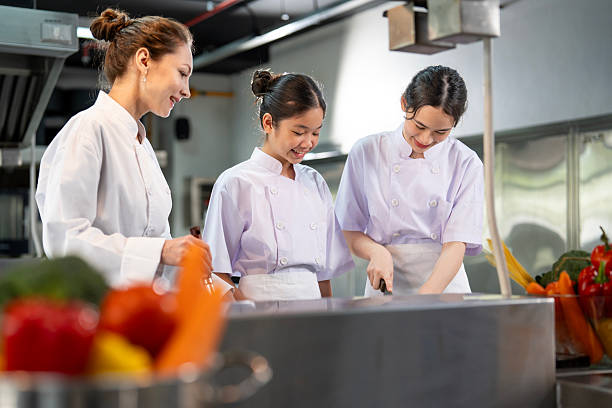 istock Professional chef is teaching young culinary class student to prepare fresh ingredient for the meal inside the restaurant kitchen for fine dining gourmet and cooking school 2234456604