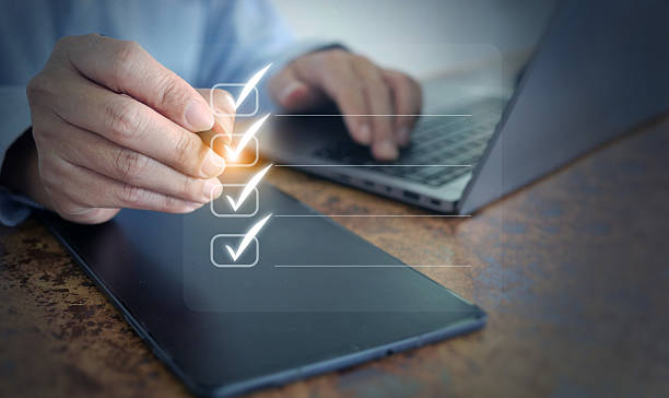 istock Business checklist concept with hand marking tasks on digital tablet and laptop, representing productivity, project planning, and workflow management in modern office. 2234457608