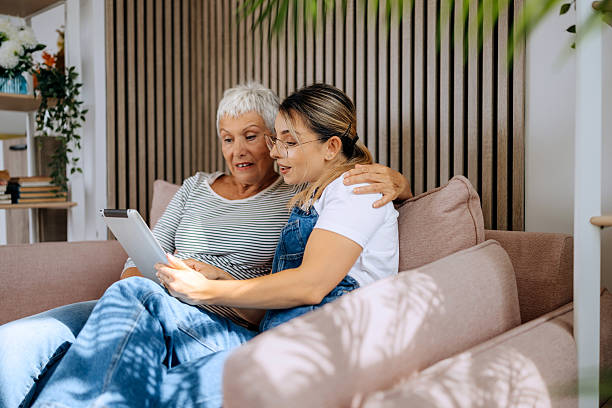 istock Senior woman and daughter using digital tablet together on sofa 2234459623