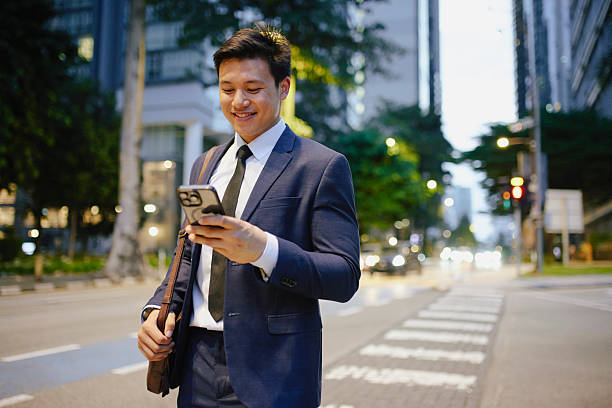 istock Smiling young businessman looking at smartphone cell phone while on evening commute in the city 2234460490