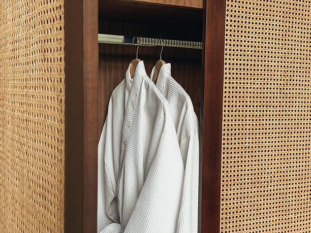 Two white clean bathrobe hanging in wooden wardrobe