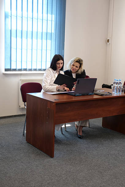istock Two professional women sitting at desk with laptop and documents, analyzing project data and planning business strategy in office meeting 2234462868