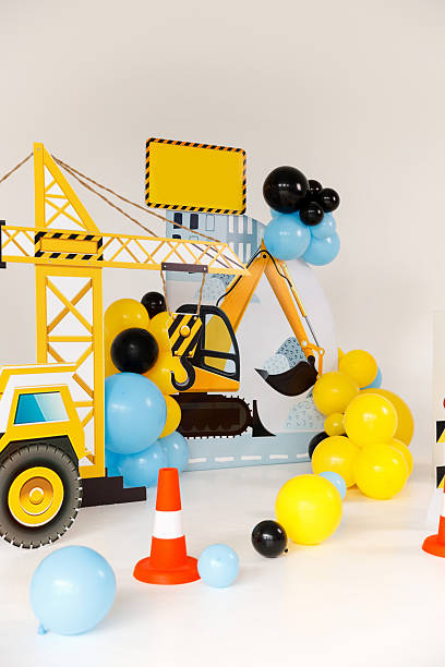 istock Creative construction site photo backdrop with cartoon excavator, crane hook, balloons, traffic cones 2234463172