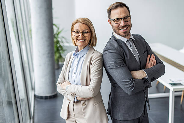 istock Two smiling business people standing back to back in office 2234464289