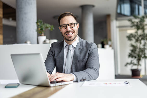 istock Smiling businessman working on laptop in modern office 2234464468