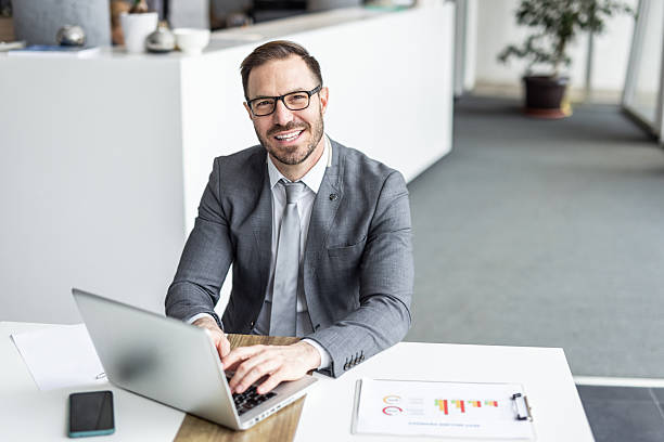istock Smiling businessman working on laptop in modern office 2234464477