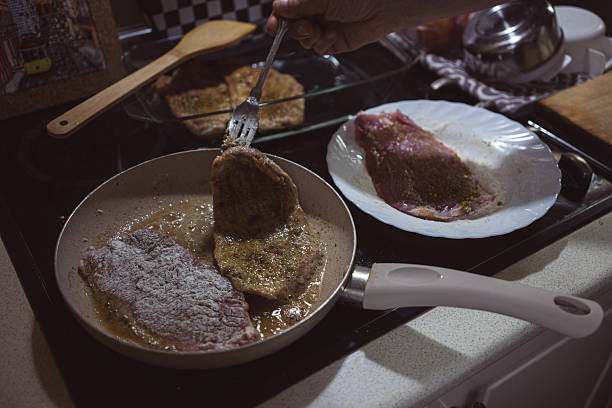 Frying meat rolled in flour on a pan, preparing food at home.