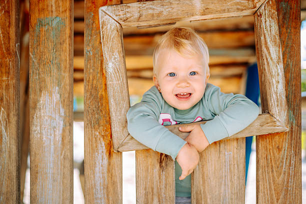 istock Smiling toddler leaning on wooden playground frame 2234466729