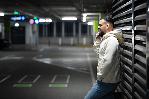 A young Caucasian man looking around and walking in an underground garage
