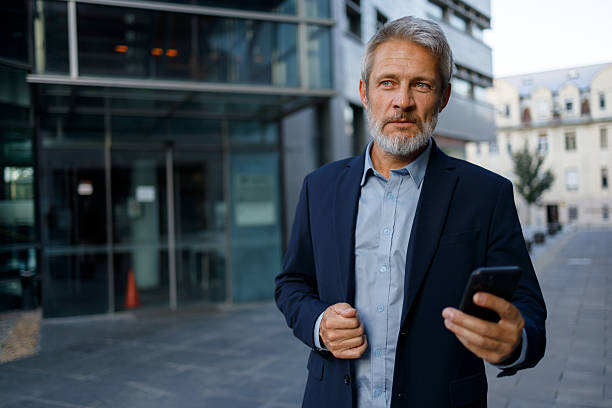 istock Professional executive striding confidently downtown, smartphone in hand, networking during workday urban environment 2234469544