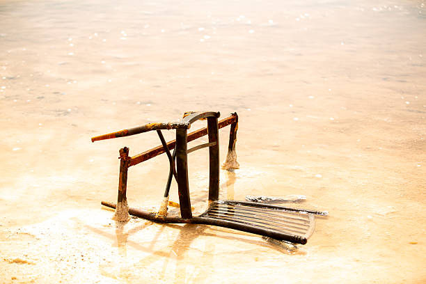 A rusty chair lying on the surface of Salt Lake, reflected in the calm water and bright sky, creating a minimal and silent composition.