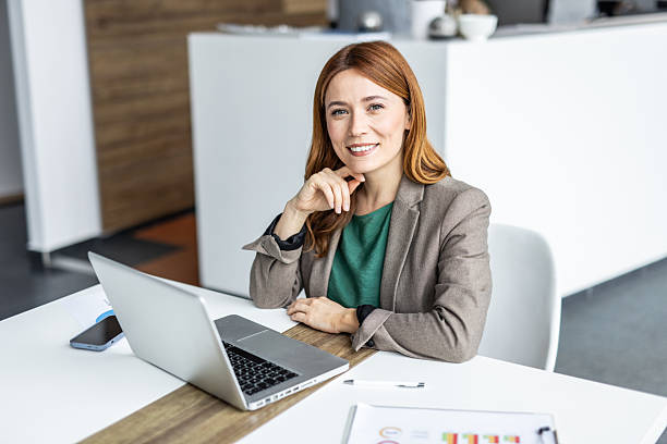 istock Businesswoman smiling while working on laptop in modern office 2234472947