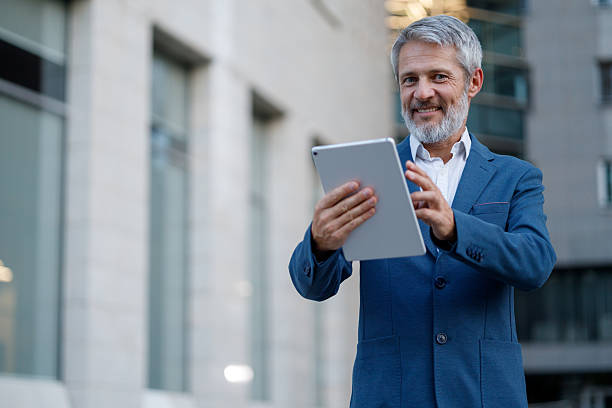istock Professional businessman navigating digital tablet, standing confidently amid modern urban skyscrapers during workday 2234474197