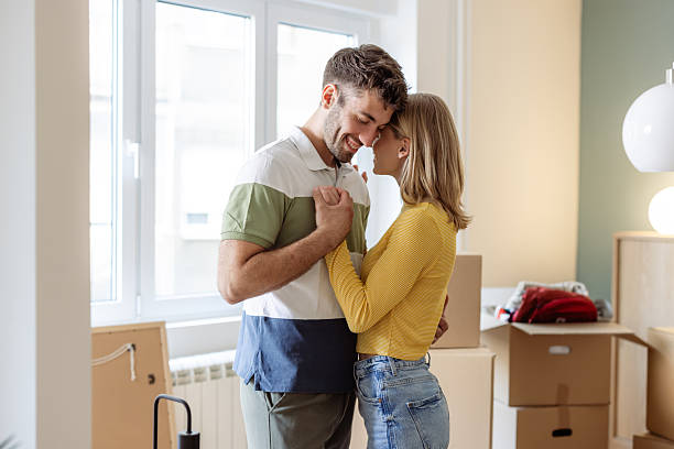 istock Young couple smiling and embracing while unpacking in their new home 2234474213