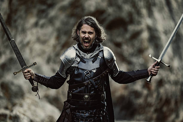 istock Black armored knight screaming with both swords raised in rocky mystical background 2234476257