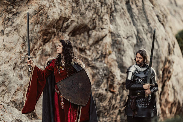 istock Celtic queen with sword and shield in rocky setting black knight blurred behind 2234477260
