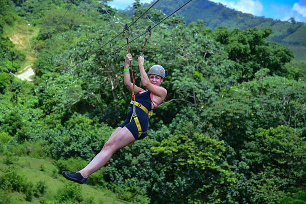 Young woman having fun zip lining through lush tropical forest in punta cana