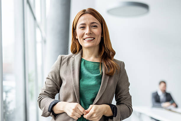 istock Smiling businesswoman buttoning blazer in modern office 2234477519