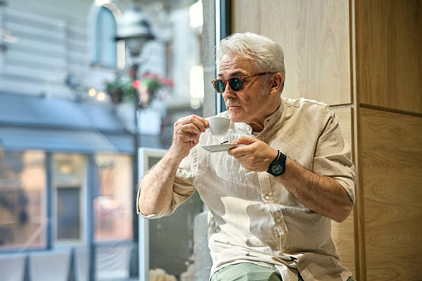 istock Senior Man Enjoying Coffee by a Cafe Window in Urban Setting 2234479177