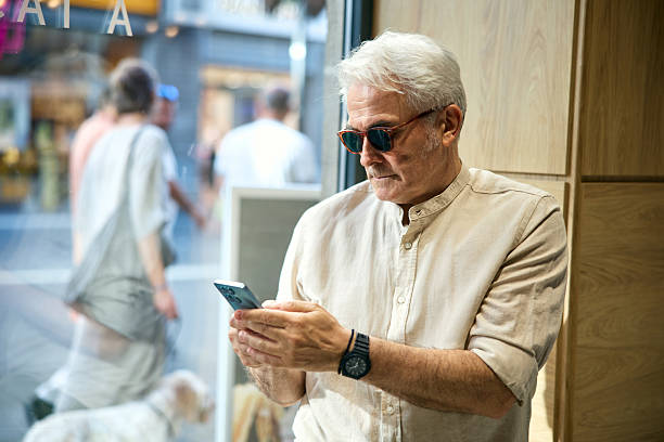 istock Elderly Man Using Smartphone Near Bright Urban Street Window 2234479196