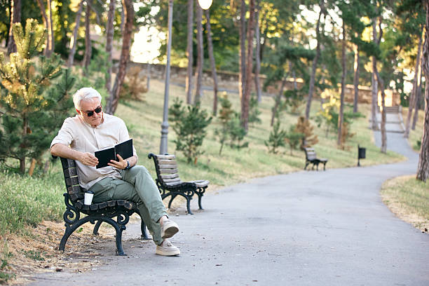 istock Senior Man Enjoying Reading Outdoors on a Park Bench 2234479436