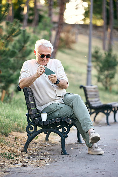 istock Older Man Relaxing in Park and Enjoying Digital Entertainment 2234479474