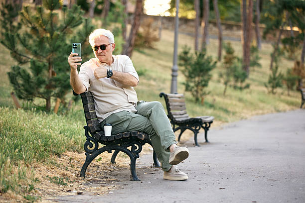 istock Senior Man Relaxing Outdoors and Using Smartphone on Park Bench 2234479511