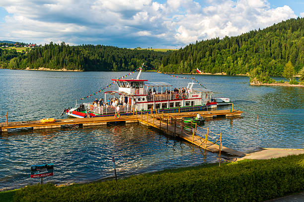 Czorsztyn Lake, Poland – August 5, 2025: Tourist boat “Halny” decorated with colorful flags is docked at pier, crowded with passengers enjoying lake cruises. Festive summer mood on the water.