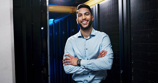 istock Happy man, portrait and server room with confidence for network control or cybersecurity service. Male person, technician or IT engineer with smile or arms crossed for connectivity in data center 2234480806