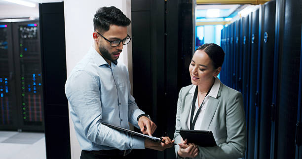 istock Man, woman and clipboard in server room for discussion, team or checklist for IT solution at company. People, cybersecurity and point with review, maintenance or information technology at data center 2234480814