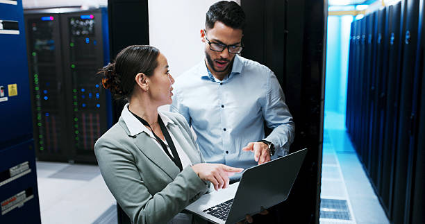 istock Server room, team and people with laptop for discussion, diagnostics or networking. IT, technician and planning with computer in datacenter for cybersecurity, system maintenance or problem solving 2234480818