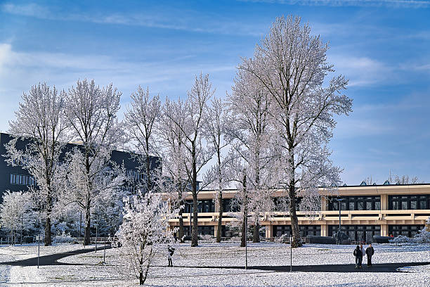 Wuerzburg, Germany - January 22, 2025: Pedestrians in the winter landscape at the Hubland campus in Würzburg. In the background the cafeteria.